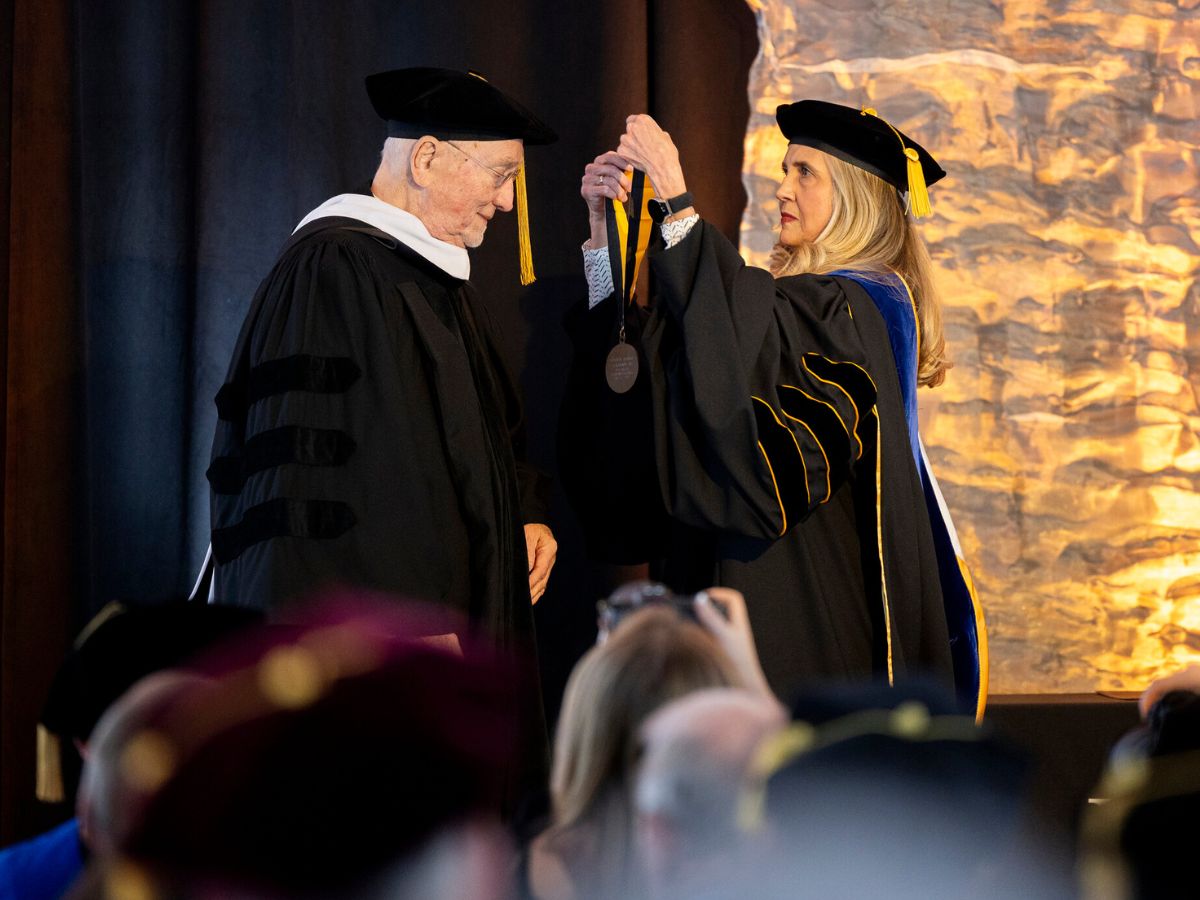 G.A. Sywassink is hooded by Walker College Dean Sandra Vannoy on December 11, 2025. Both wear academic regalia.