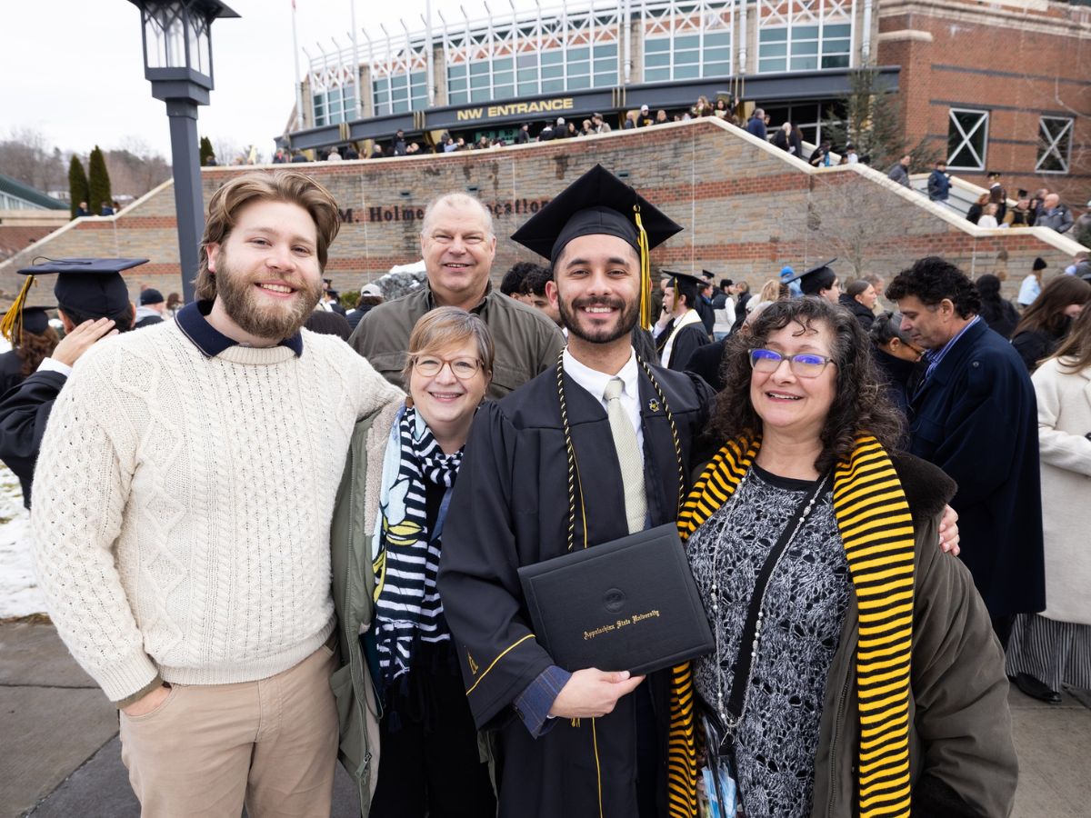 Jonah Smith, wearing App State regalia, stands with his family outside the Holmes Convocation Center on December 12, 2025 following his App State Commencement