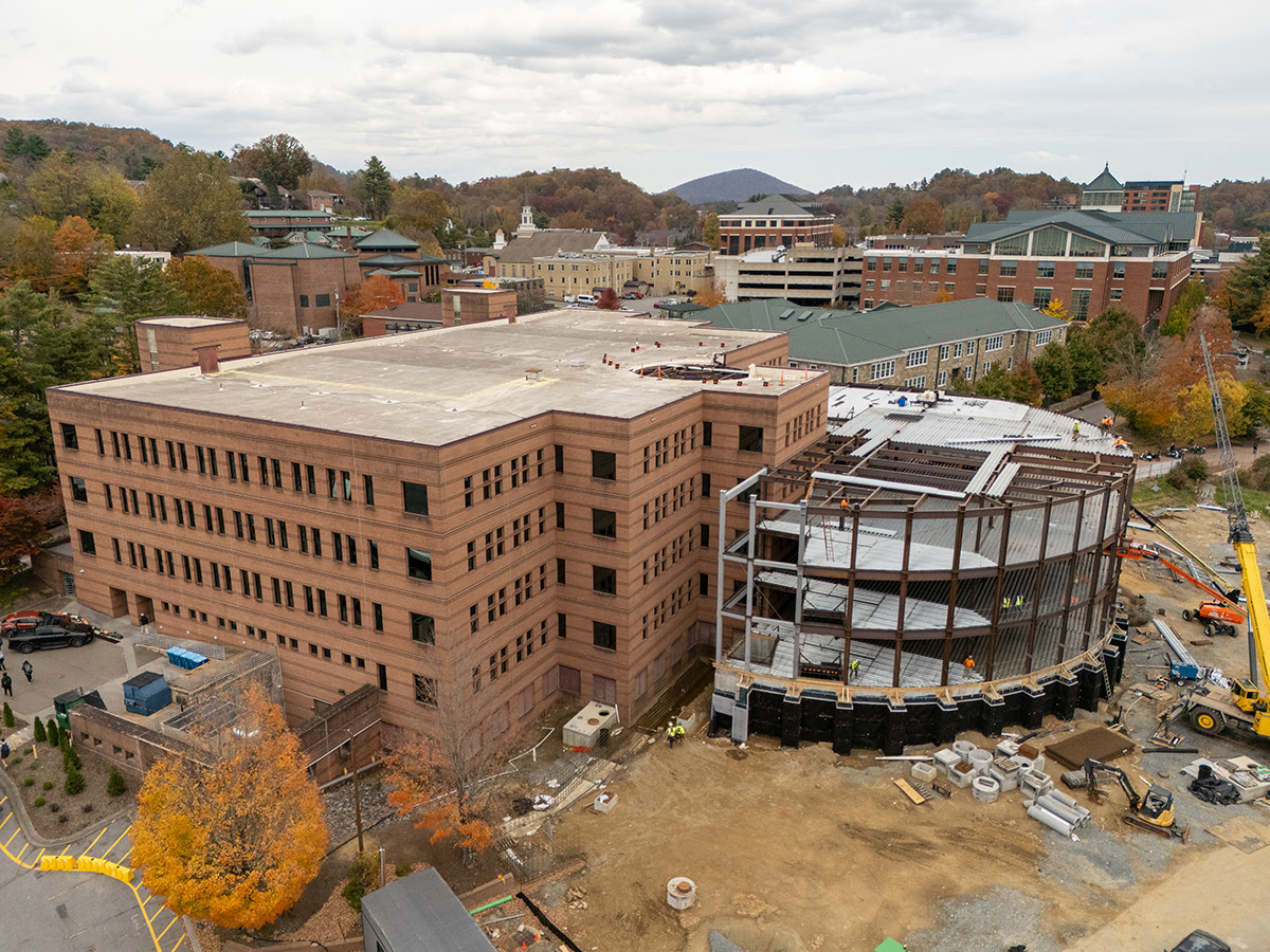 Photo by Wes Craig Peacock Hall and it's addition, under construction, aerial view of the autumn day a time capsule beam was installed (October 23, 2025). Construction workers and equipment are visible, as well as