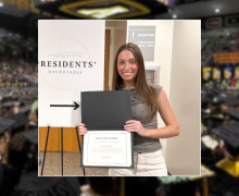 Emily Bills stands with a Presidents' Roundtable sign, holding a certificate that says "High Grit Leader"
