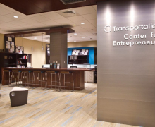 Inside the Center for Entrepreneurship is comfortable seating, stools at a desk, bookshelves, and a wall that features the center name.