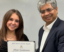 Jillian Goldstein, left, accepts a certificate with the text "best honors poster award" from Dr. Santosh Nandi.
