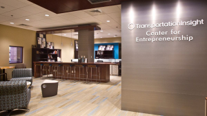 Inside the Center for Entrepreneurship is comfortable seating, stools at a desk, bookshelves, and a wall that features the center name.