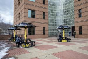 Appalachian students pause between classes to charge their phones at the three new solar-powered picnic tables available on the first-floor patio of Peacock Hall. Photo by Marie Freeman