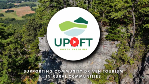 An Uplift logo includes mountains, valleys and waterways and is displayed over a North Carolina outdoor scene