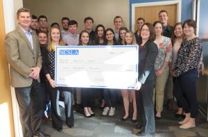 NCSLA Stamping Office Chair Danielle Wade, holding check at left, with Brantley Risk & Insurance Center Director Dave Marlett, far left, Walker College of Business Dean Heather Norris, holding check at right, and student participants of the 2018 London trip