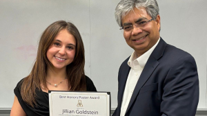 Jillian Goldstein, left, accepts a certificate with the text "best honors poster award" from Dr. Santosh Nandi.