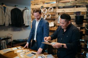 Appalachian alumni Bradley Rhyne ’07, left, and Filipe Ho ’07 review fabric swatches at their OLE MASON JAR menswear shop in Charlotte. Photo submitted