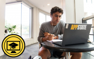 Zach Covington, a first-year exercise science major at Appalachian, looks at his laptop while taking notes. Photo by Chase Reynolds