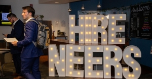 An App State student in front of "HIRE NEERS" sign